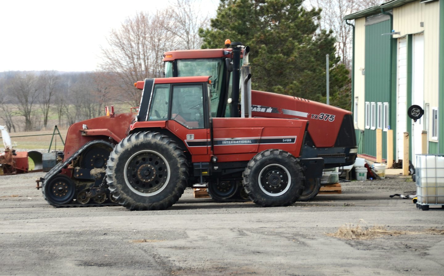 Ein roter Traktor und ein Mähdrescher parken auf einem Feldweg.